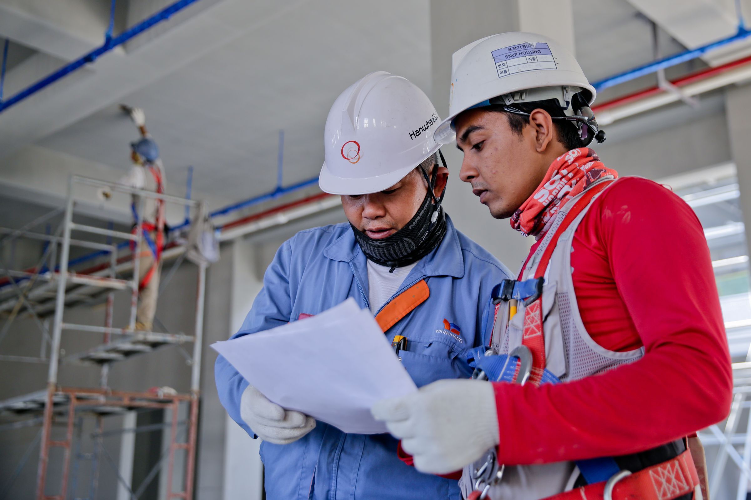 Two engineers in hard hats reviewing a drawing on site