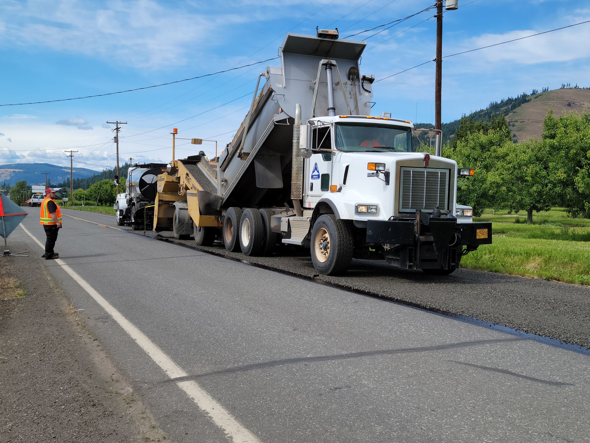 Tipper truck and paving crew on a road construction site
