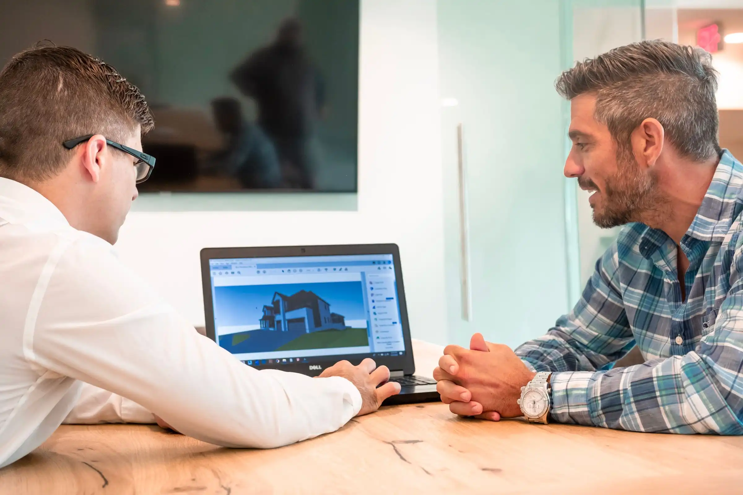 Two professionals reviewing a building design on a laptop