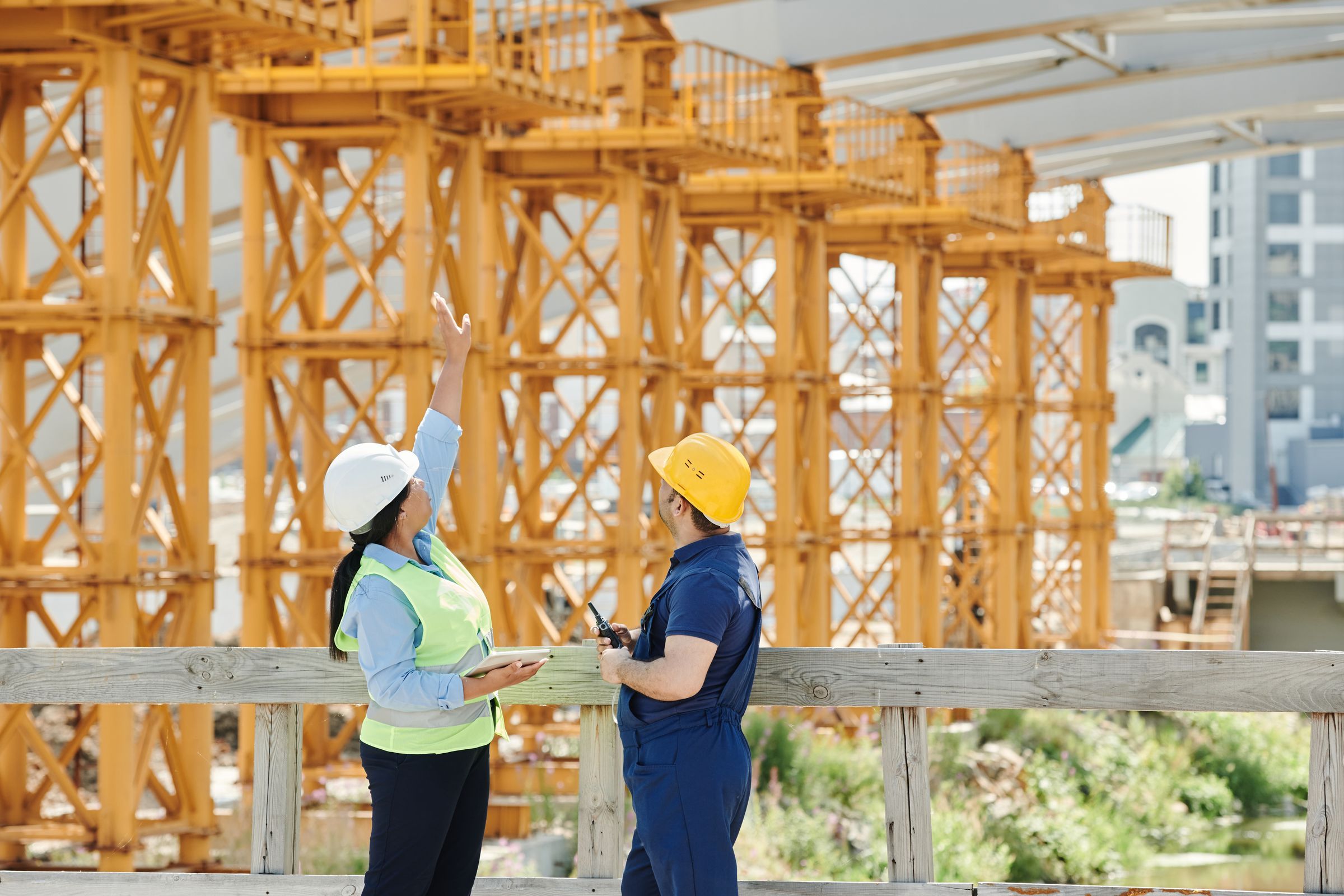 Two engineers checking a tablet beside a steel frame on site