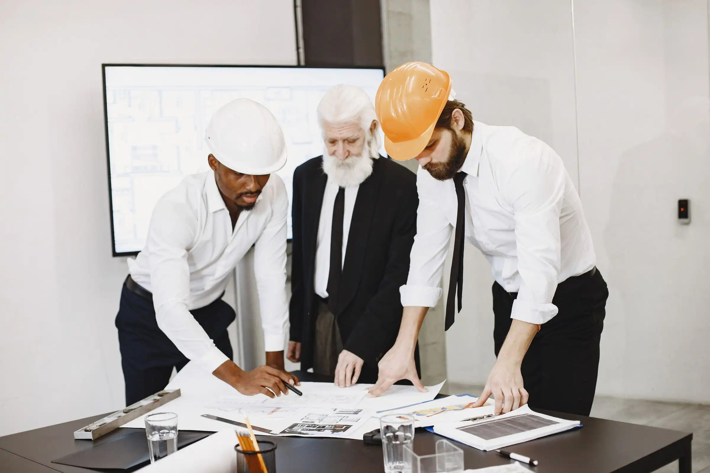 Three professionals reviewing tender drawings